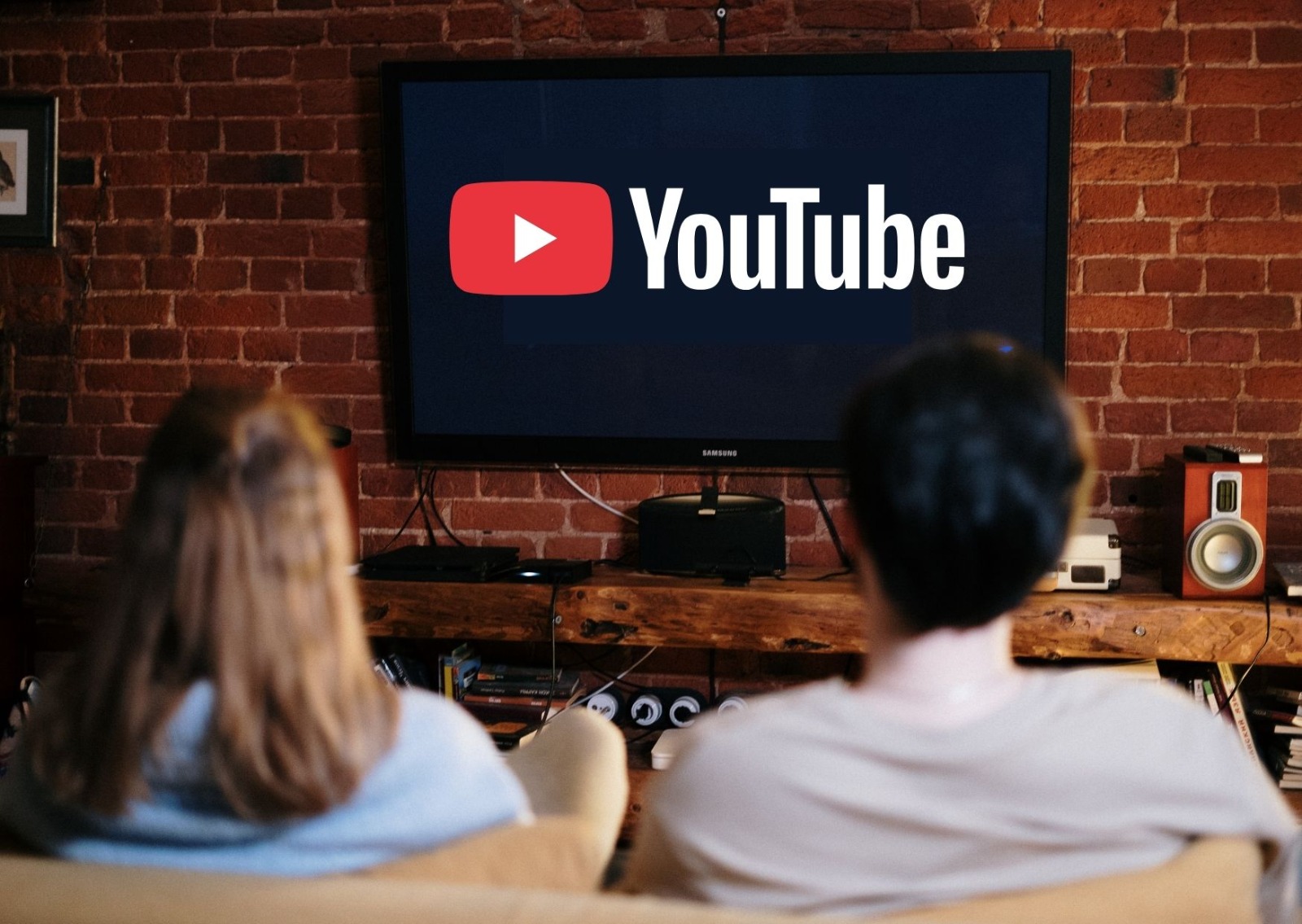 Two people look at a television screen with the YouTube logo on it.